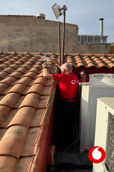 un técnico de Vodafone en un tejado arreglando una antena