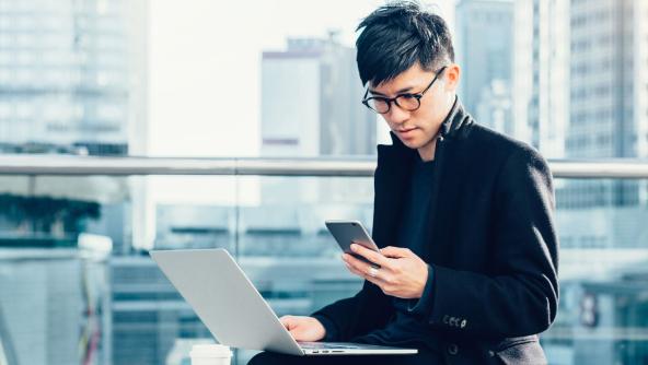 un chico usando un portátil y un smartphone