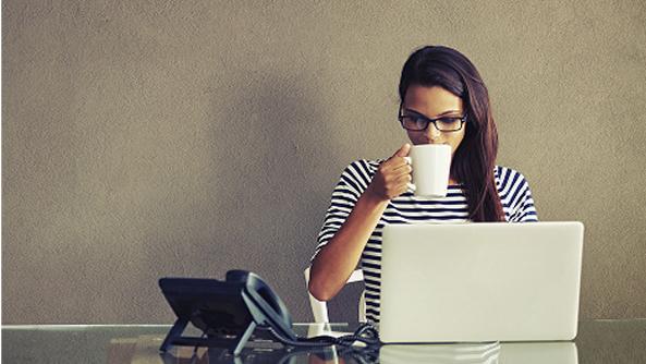 una chica teletrabajando mientras bebe una taza de café
