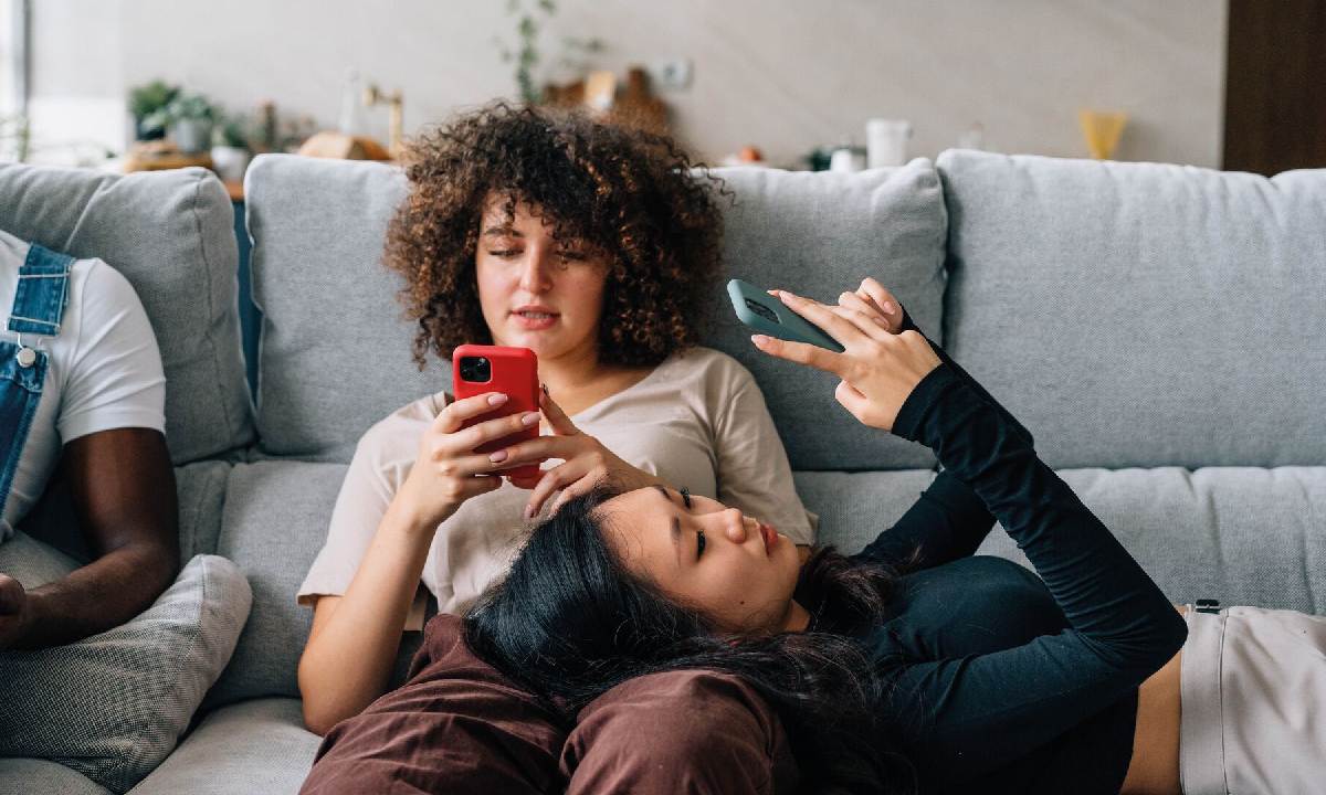 un par de chicas jóvenes en el sofá usando su smartphone