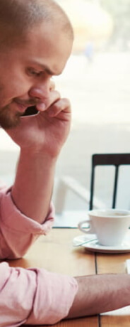 un hombre hablando por el móvil mientras trabaja con un portátil